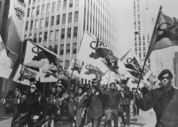 Black panturing marching with flags during Free Huey protest.