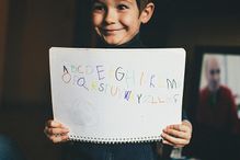 Cute Little Boy Smiling While Holding Alphabet Book