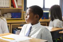 School Boy Sitting at Desk among students.