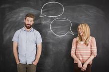 Young couple with speech bubble on blackboard, studio shot