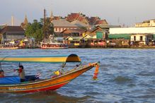 Thailand coastline showing a boat and land architecture during a cloudy day.