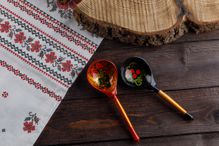 wooden Russian hand-painted spoons and tablecloth with a traditional pattern on natural wooden background. Top view.