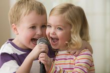 Caucasian brother and sister singing into microphone