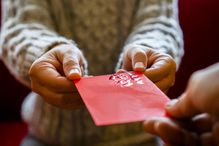 Close up of one person giving a red envelope to another.