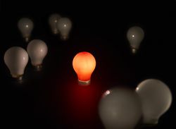 A red lightbulb lit amongst unlit white bulbs
