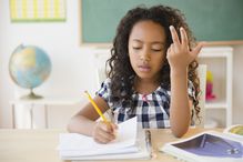 A student counting on fingers in classroom