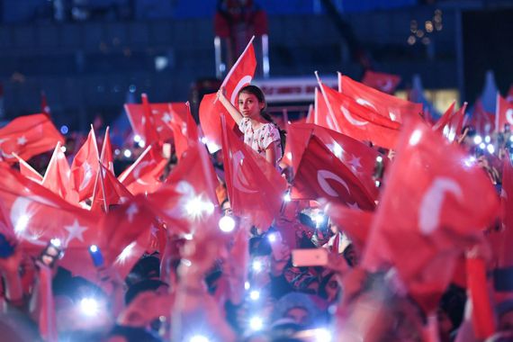 People wave Turkish national flags as they stand at the Ataturk International Airport in Istanbul on July 15, 2019. - Turkey commemorates, on July 15, 2019 the third anniversary of a coup attempt which was followed by a series of purges in the public sector and changes to boost Turkish President's powers.