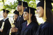 Group of graduates with diplomas on university campus (differential focus)