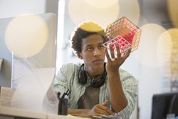 Businessman examining cube at his desk in an office