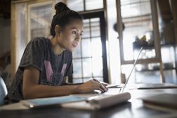 Focused young woman working at laptop in office