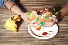 A woman eats a burger, demonstrating the act of consumption. To sociologists, there's much more to consumption than the simple act of taking in or using up resources.