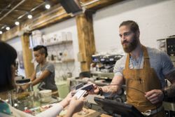 Customer paying barista with credit card in cafe