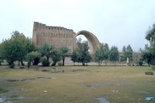 The Sassanian Arch behind a line of trees.