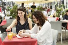 Two women chatting and having breakfast at sidewalk cafe, Milan, Italy