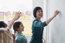 Teacher writing on blackboard with students