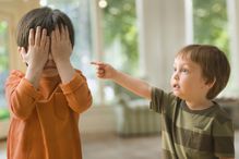 Mixed race boy pointing at brother who's covering his eyes