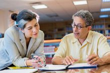 Teacher helping adult student in library