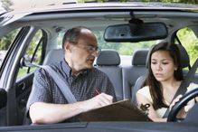 Teenage girl sitting in car with driving instructor