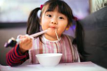 Toddler girl having noodles in restaurant