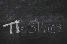 Hand-written Pi numbers on a black chalkboard