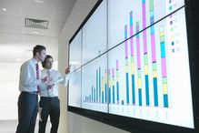 Business people look at a large display of data