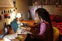 Student sitting at desk in bedroom looking at phone