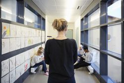 Rear view of teacher looking at students in school corridor