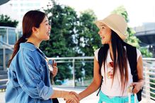 Smiling Friends Shaking Hands While Standing Outdoors