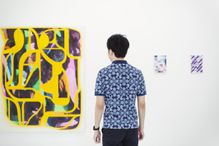 A man in an art gallery looks at abstract art.