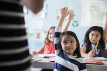 Little girl raising her hand in the classroom