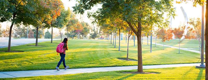 A female student walks along a picturesque pathway at UC Merced.