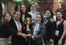 #ParaTodosVerem Seis mulheres jovens e um homem de meia idade na foto, todos estão sorrindo. Duas estão segurando o troféu.