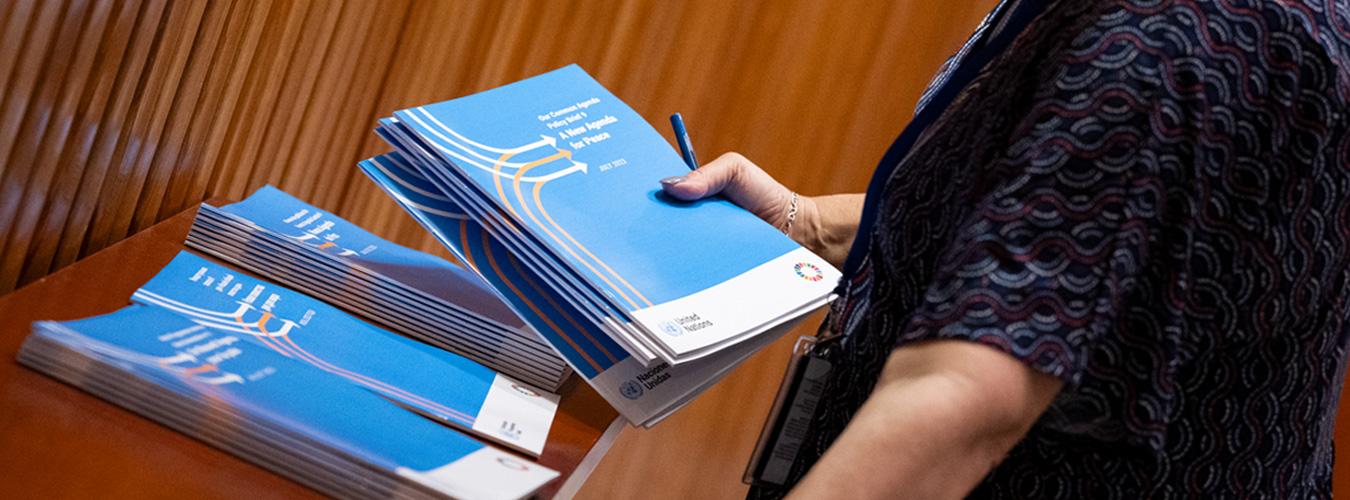 A woman holds copies of Our Common Agenda with more seen on a table