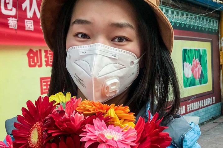 young woman with mask holding flowers