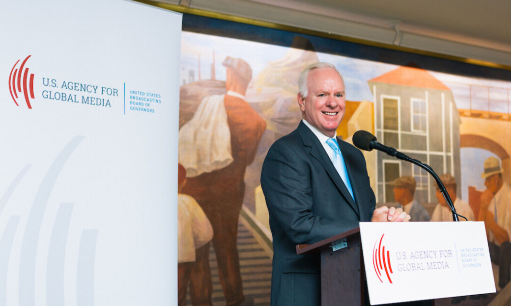 man smiling behind podium