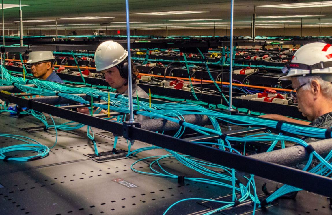 TACC employees work on the network cabling above the racks of Frontera