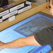 Student examines archived work on large touch screen display.