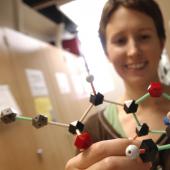 Student in lab holding a chemistry model.