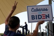 A woman holds up a sign that reads "Cubans with Biden."